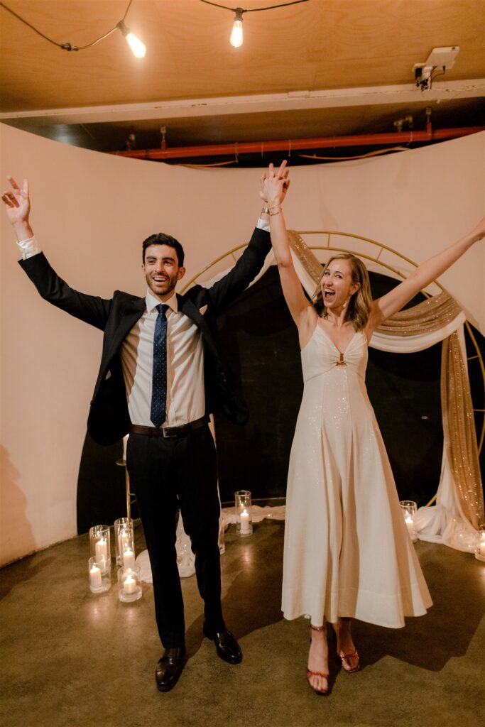 Bride and groom with hands in the air as they are pronounced husband and wife.