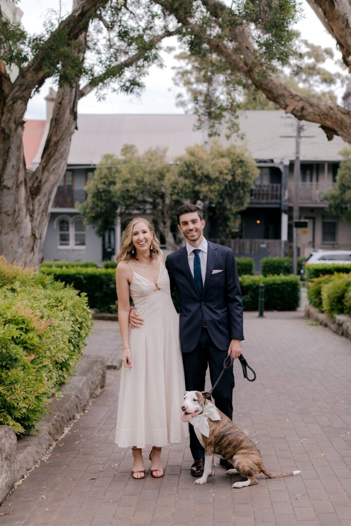 Bride and groom pose in street with their dog.