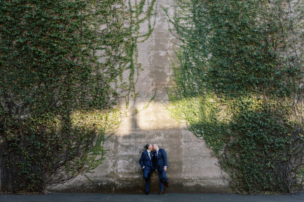 John and Jeff leaning against sandstone wall covered in ivy on their wedding day, The Rocks Sydney