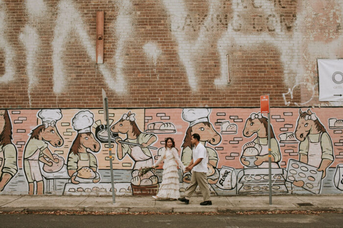 Bride and groom walking past mural on street